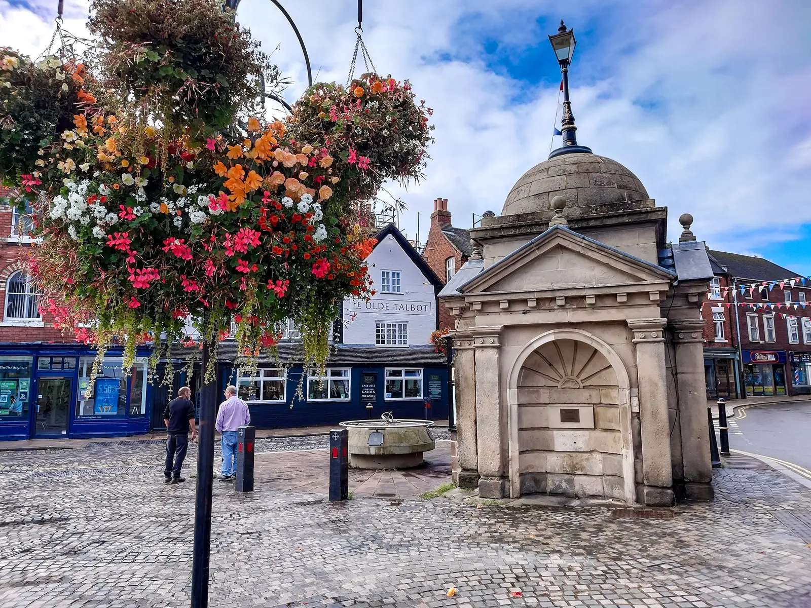A historic building in Uttox, with a hanging basket in the fore ground.